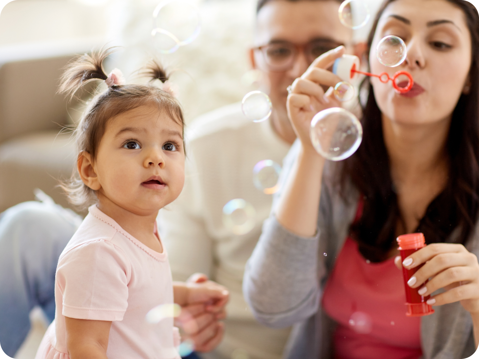 Man and woman blowing bubbles for their child.