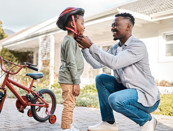 Man helping his son put on a bicycle helmet.